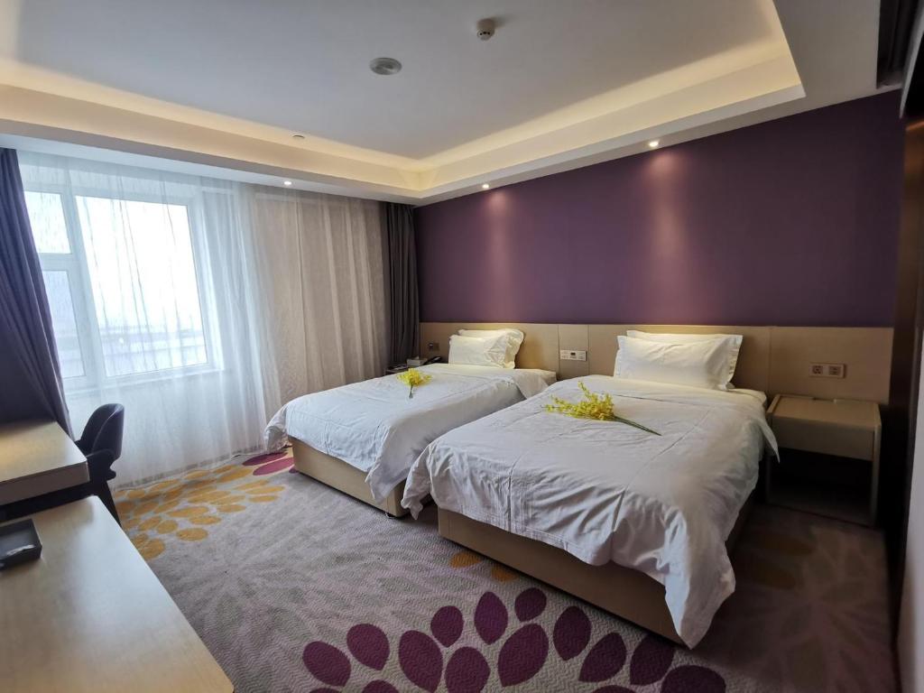 ein Hotelzimmer mit 2 Betten und einer lila Wand in der Unterkunft Lavande Hotel (Changchun Yiqi Branch) in Changchun