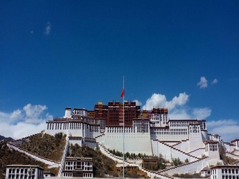 Lavande Hotel (Lhasa City Government Xizang University Branch) في لاسا: مبنى ابيض كبير عليه علم احمر