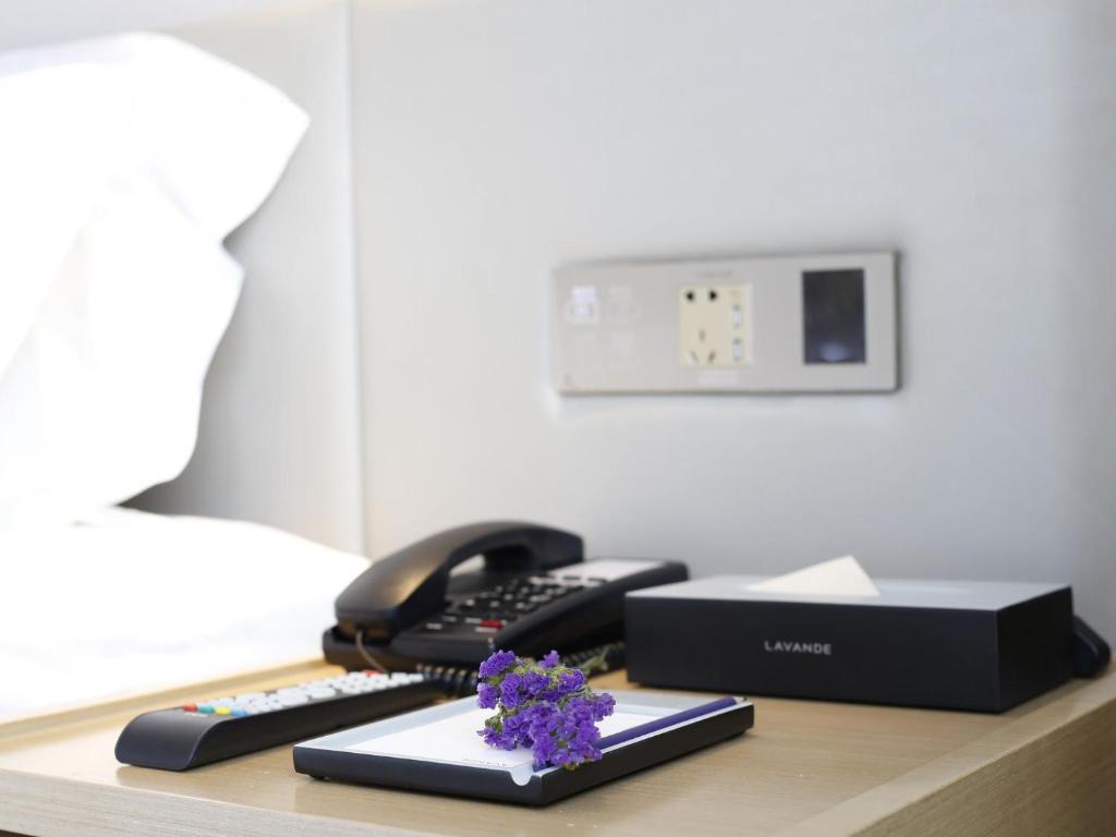 a desk with a phone and purple flowers on it at Lavande Hotel (Linfen Binhe East Road Yujing Shuicheng Branch) in Linfen