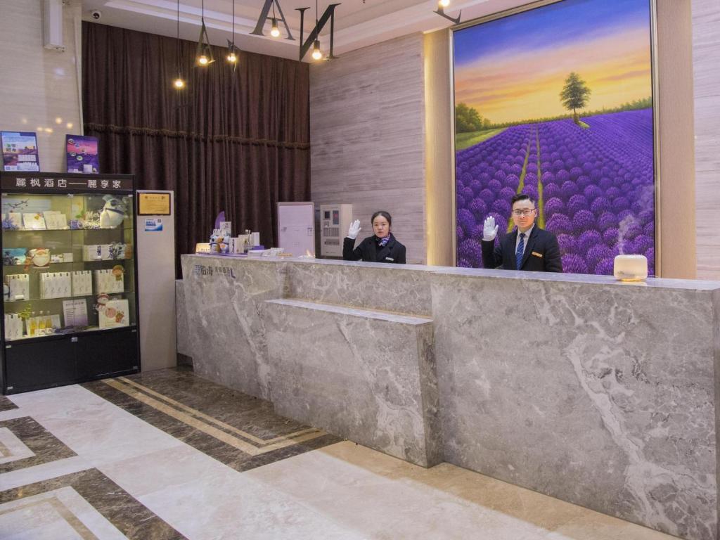 two people standing at a counter in a store at Lavande Hotel Xiantao Xintiandi International Plaza in Xiantao