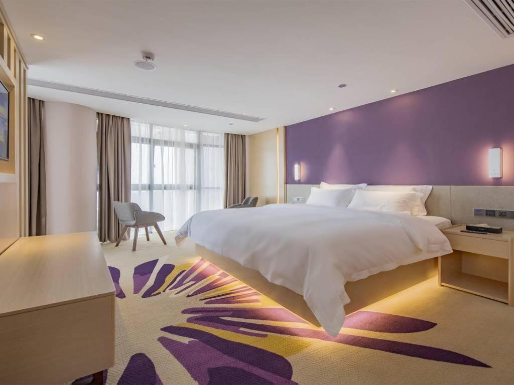 ein Schlafzimmer mit einem großen Bett und einer lila Wand in der Unterkunft Lavande Hotel Nanchang Shuanggang Metro Station Caida University in Nanchang