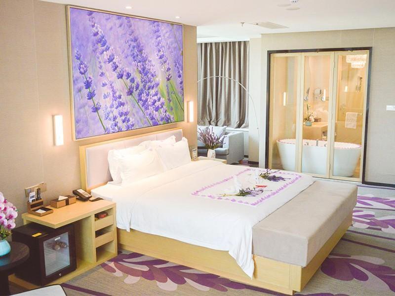 1 dormitorio con 1 cama grande y una pintura morada en la pared en Lavande Hotel Xuzhou New Town Midea Plaza, en Xuzhou