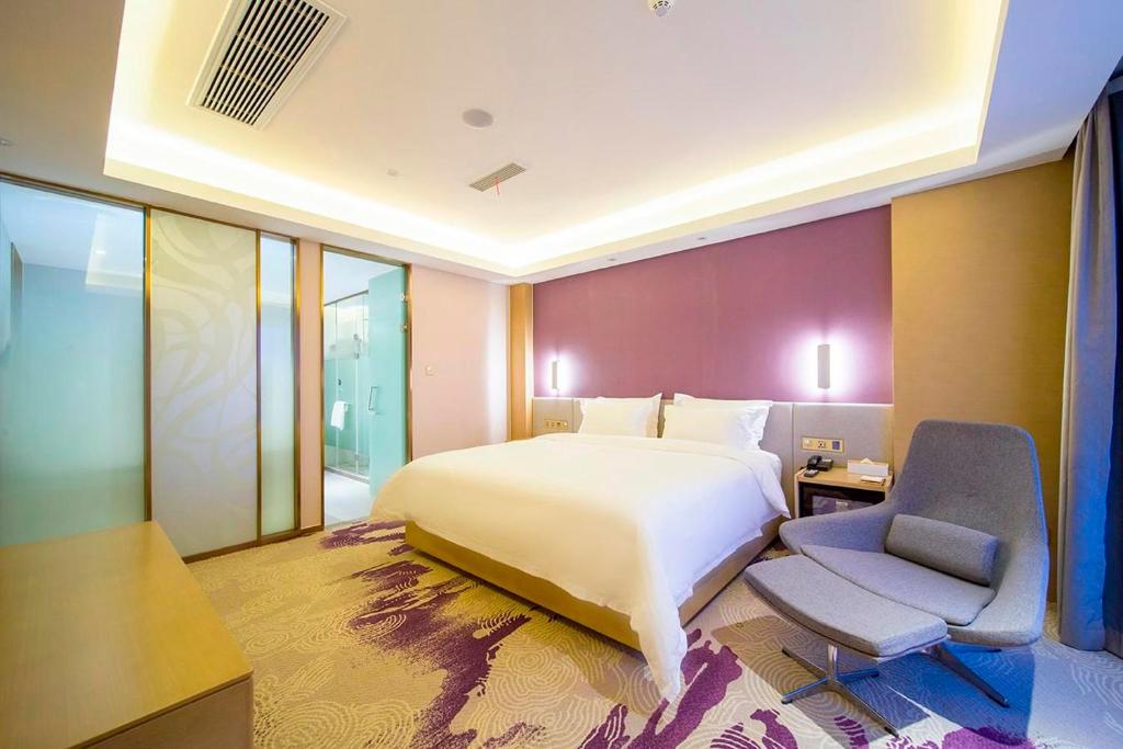 a bedroom with a large bed and a chair in it at Lavande Hotel (Yangzhou Jiangwangshui Street RT-Mart Branch) in Yangzhou