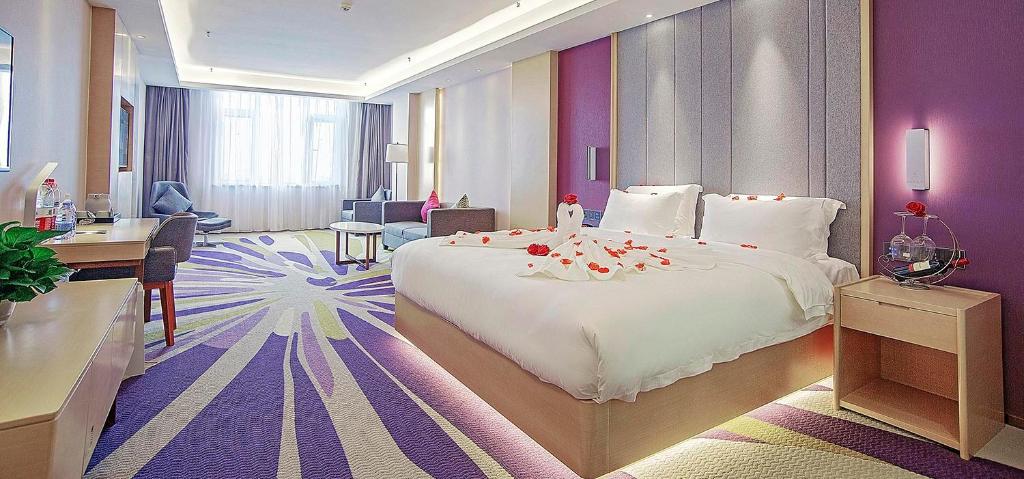 邯鄲市にあるLavande Hotel Handan Congtai Park New Century Plazaの大きなベッドとデスクが備わるホテルルームです。