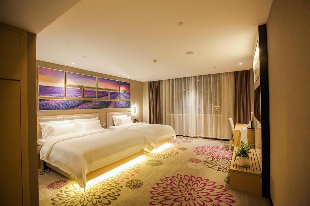 1 dormitorio con 1 cama grande y una pintura grande en Lavande Hotel Taizhou Railway Station Zhongjia Branch en Taizhou