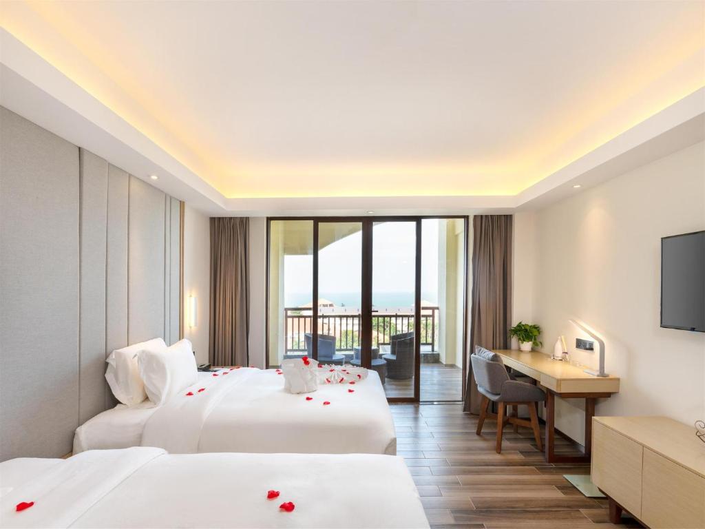 a hotel room with two beds and a desk at Lavande Hotel Haikou Binhai Avenue in Haikou