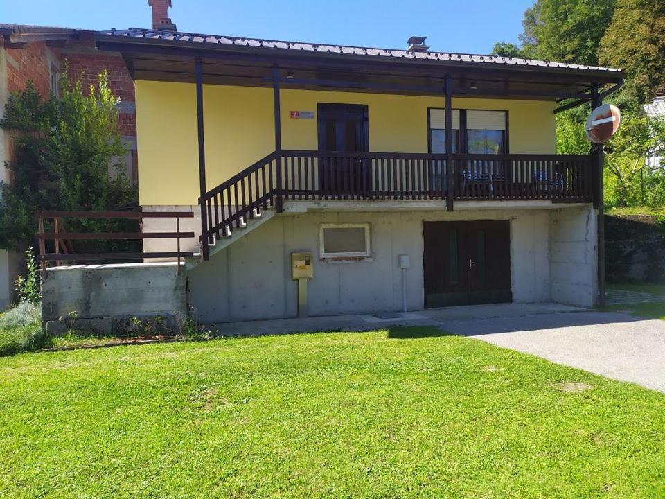 a yellow house with a balcony and a yard at Hiša Belin in Podbela