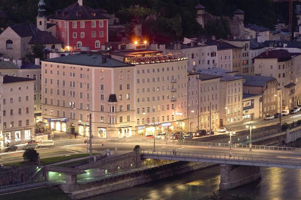 Hotel Stein - Adults Only في سالزبورغ: مدينة بالليل فيها جسر ومباني