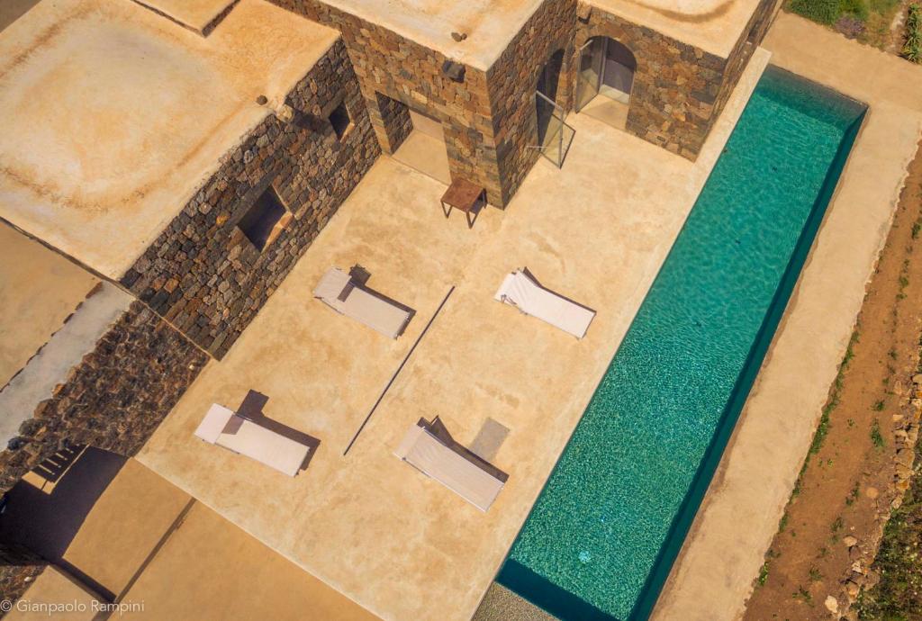 an overhead view of a pool with chairs and a table at Dammuso Kaddiuggia Antica Pantelleria in Pantelleria
