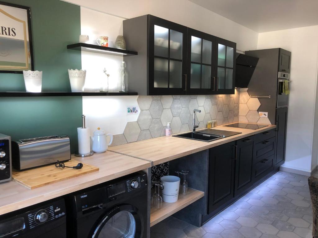 une cuisine avec des placards noirs, un évier et un lave-linge dans l'établissement BedinReims luxe wonderful calm in city center, ideal for 2 adults and 3 children free parking, à Reims