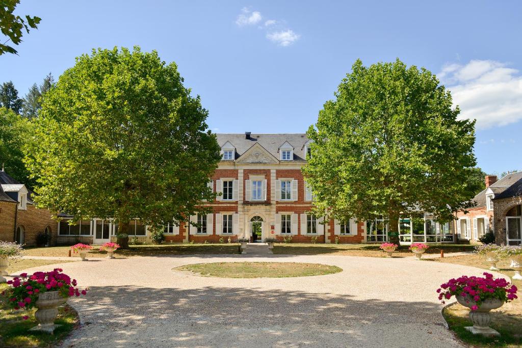 una casa grande con árboles delante de ella en Logis Domaine De Valaudran, en Salbris