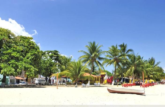 a beach with palm trees and a boat on the sand at Aluga-se apartamento em Ponta de Areia in Itaparica Town