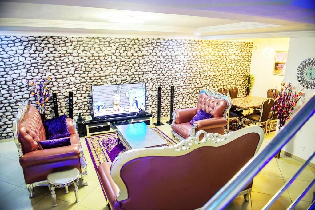 a living room with chairs and a flat screen tv at Cc & Cg Homes Luxury 4 Bedroom Semi-Detached House In Abuja, Nigeria in Abuja