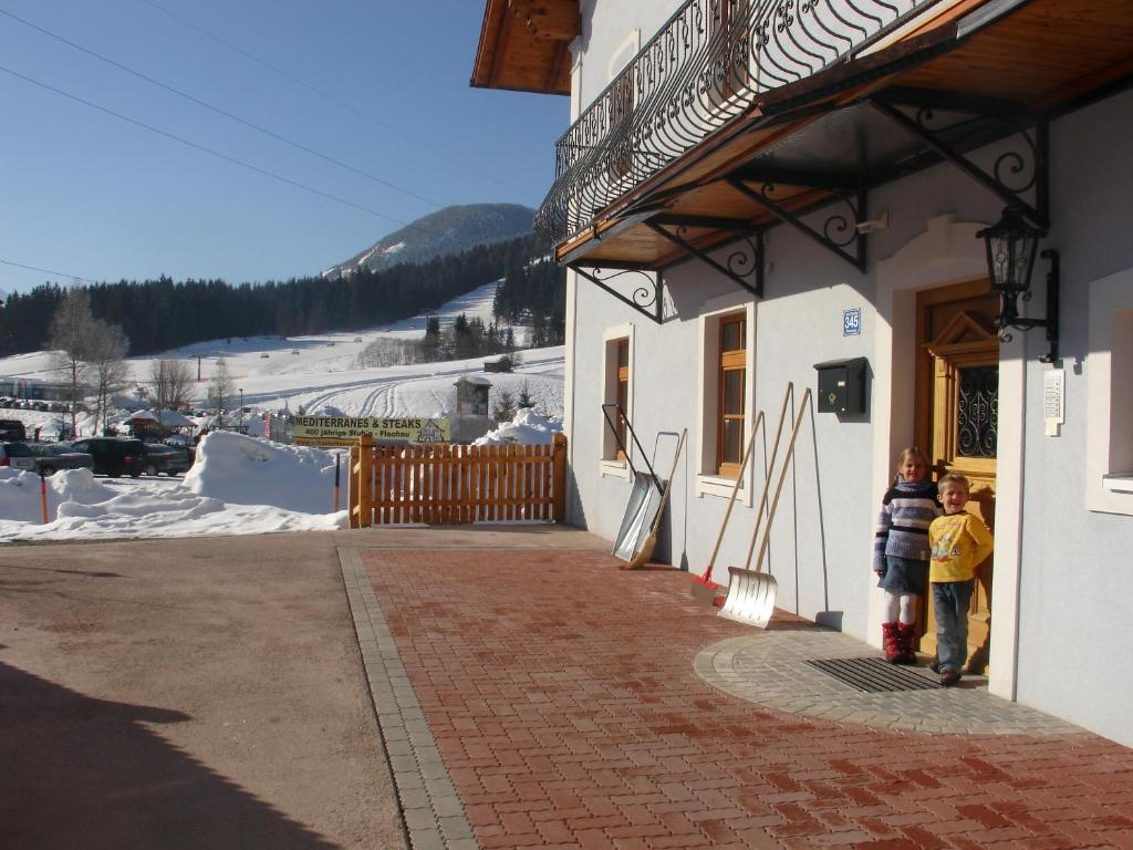 zwei Kinder stehen vor einem Gebäude im Schnee in der Unterkunft Haus Bliem in Flachau