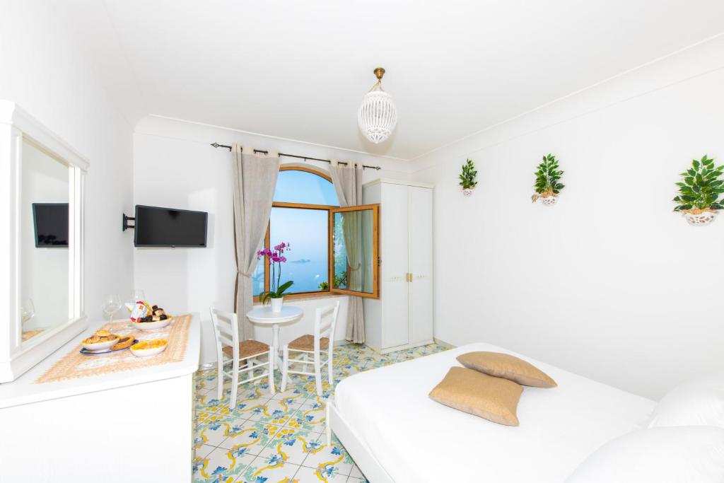 Cette chambre blanche comprend un lit, une table et des chaises. dans l'établissement La Borragine Rooms, à Positano