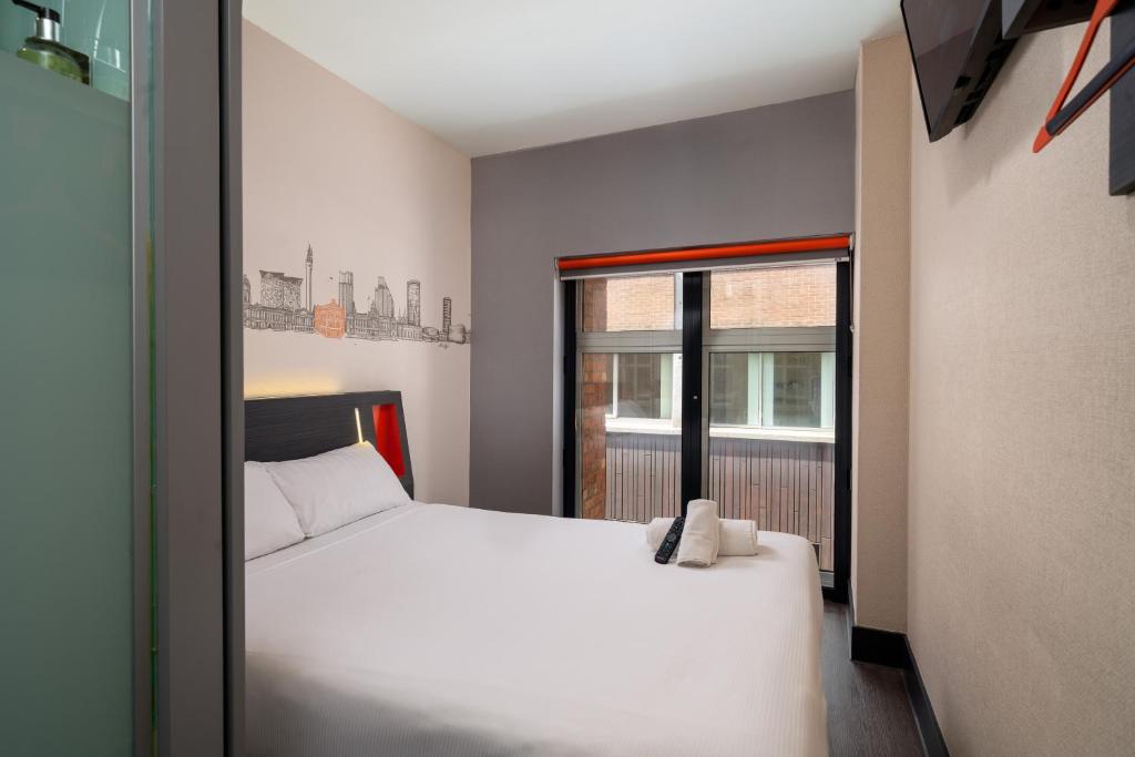 1 dormitorio con cama blanca y ventana en easyHotel Birmingham, en Birmingham