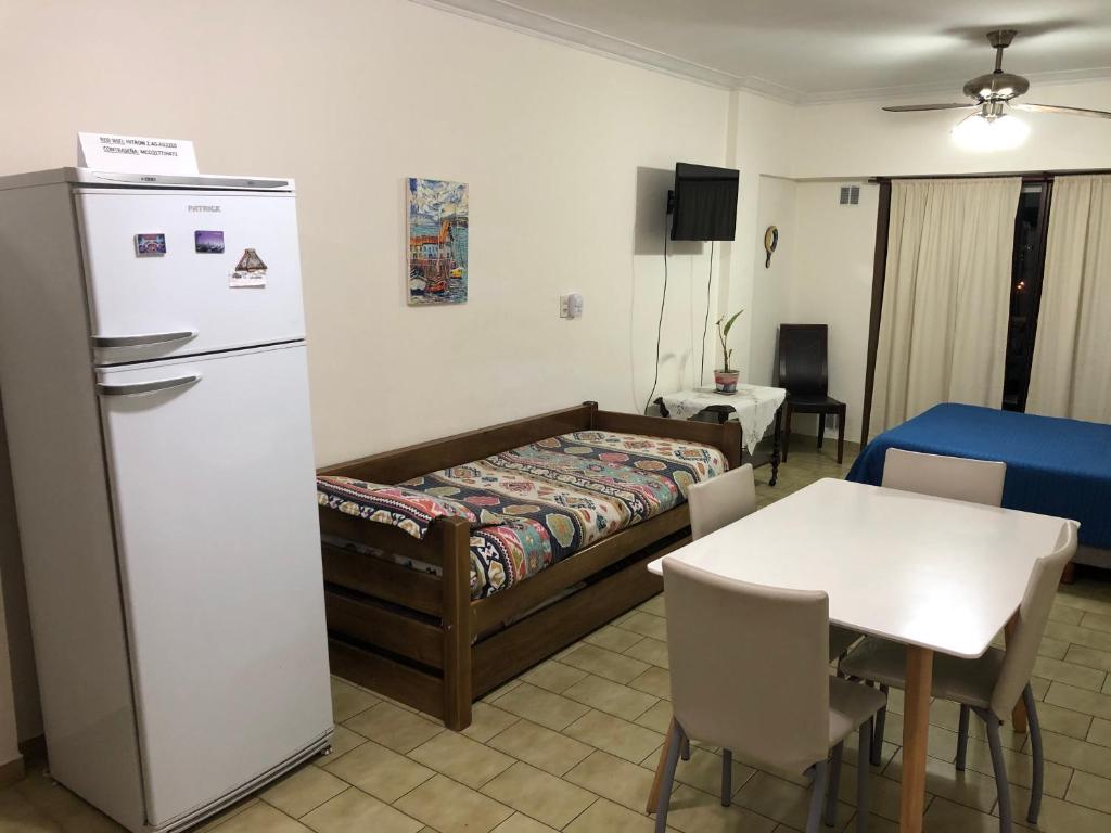 a room with a bed and a table and a refrigerator at Apartamento Pacifico Altos Balcony in Bahía Blanca