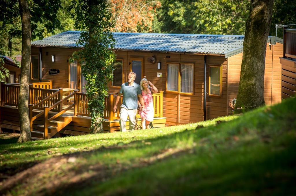 a man and woman standing in front of a log cabin at St. Ives Holiday Village in St Ives