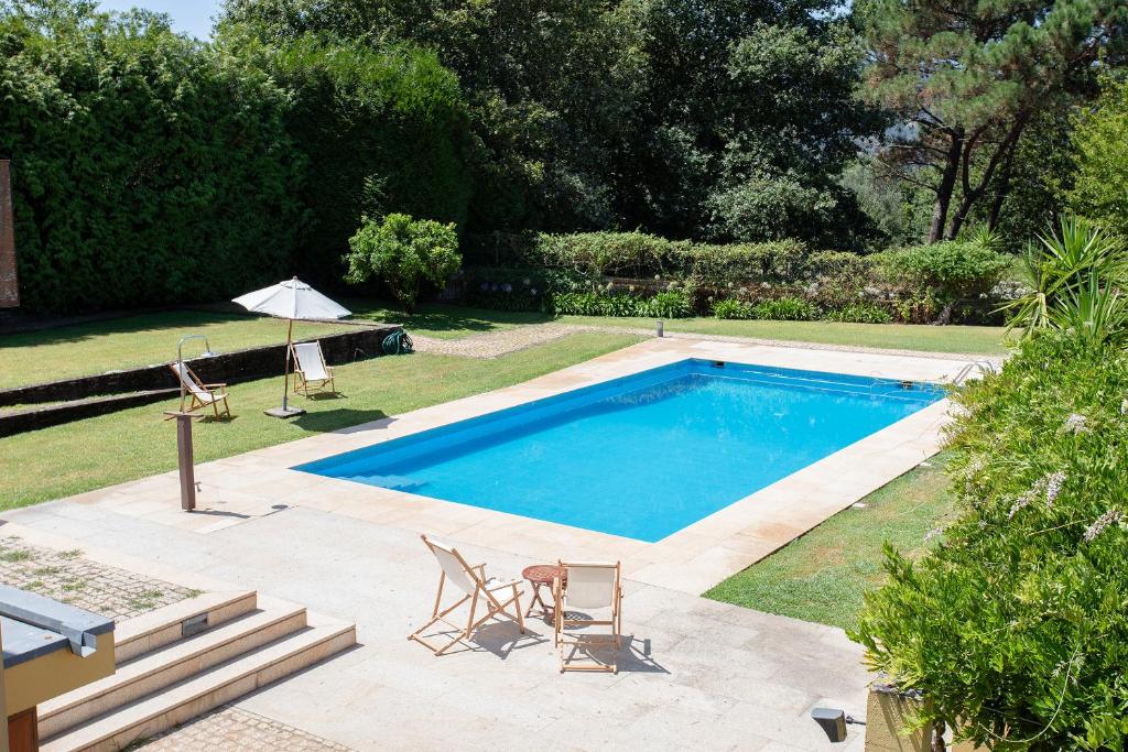 uma piscina com duas cadeiras e um guarda-sol em Liiiving in Caminha | Countryside Pool House em Caminha