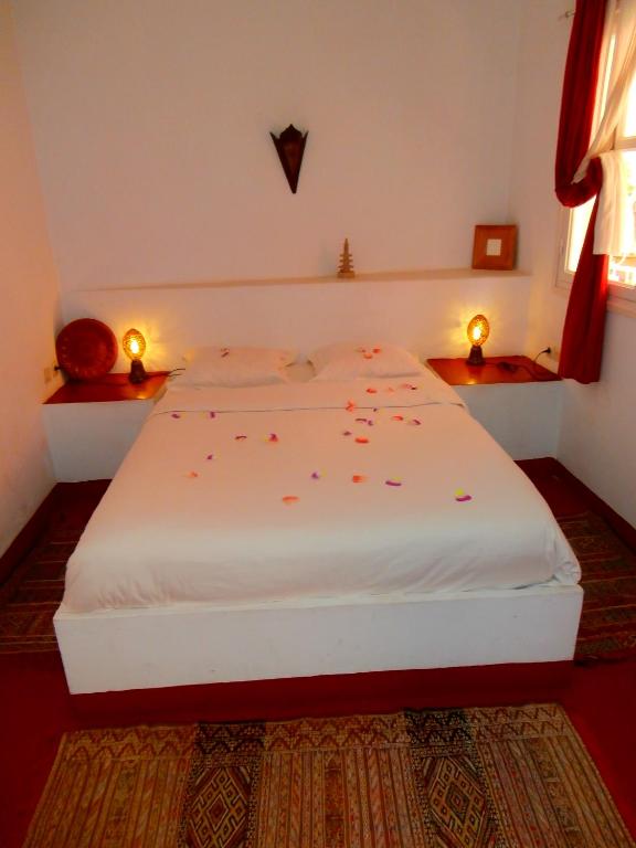 a bedroom with a white bed with confetti on it at Maison Xanadu in Sidi Ifni