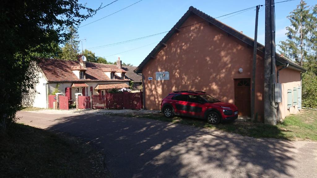 ein rotes Auto, das vor einem Gebäude parkt in der Unterkunft Maison d'Othe in Saint-Mards-en-Othe