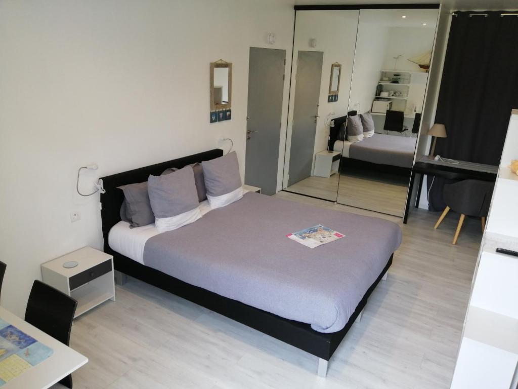 een slaapkamer met een groot bed en een spiegel bij Chambre spacieuse, moderne et très confortable à Perros-Guirec in Perros-Guirec