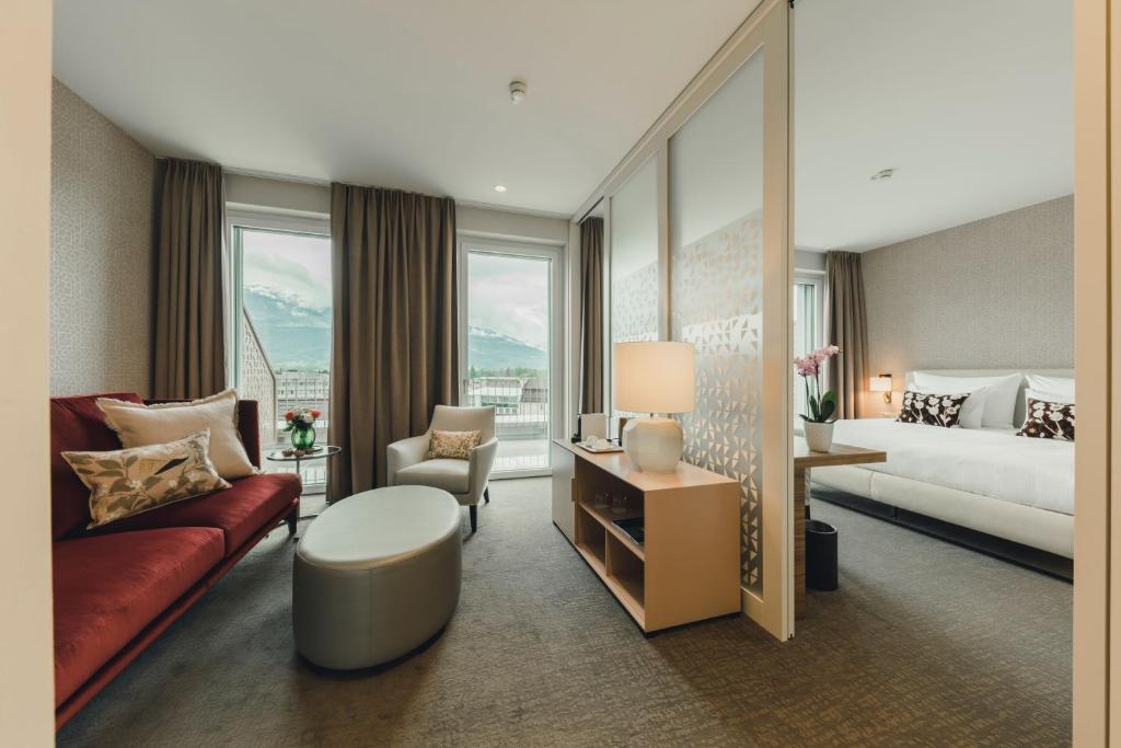 a hotel room with a couch and a bed and window at Central by Residence Hotel in Vaduz