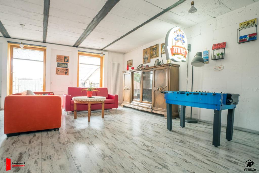 a living room with a pool table and red chairs at Apartamenty na Podhalu in Nowy Targ