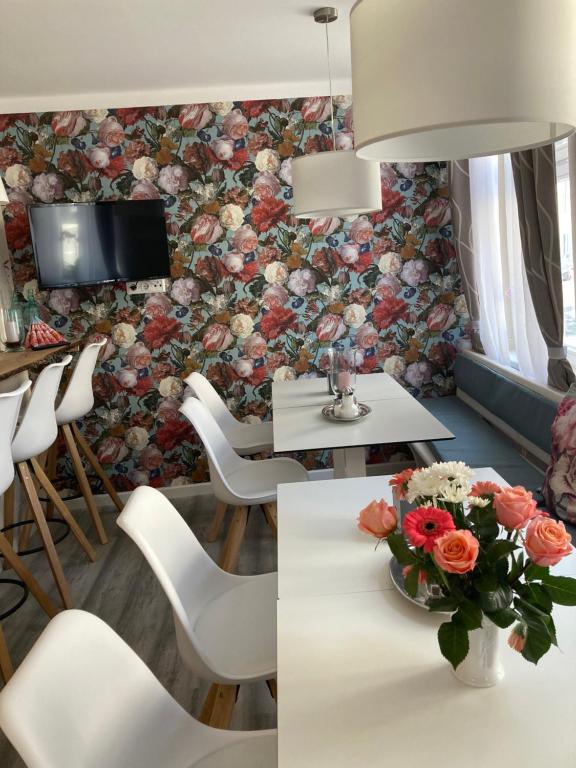 Zimmer mit einem Tisch und Stühlen sowie einer Blumenwand in der Unterkunft Hotel-Pension Adler Untertürkheim in Stuttgart