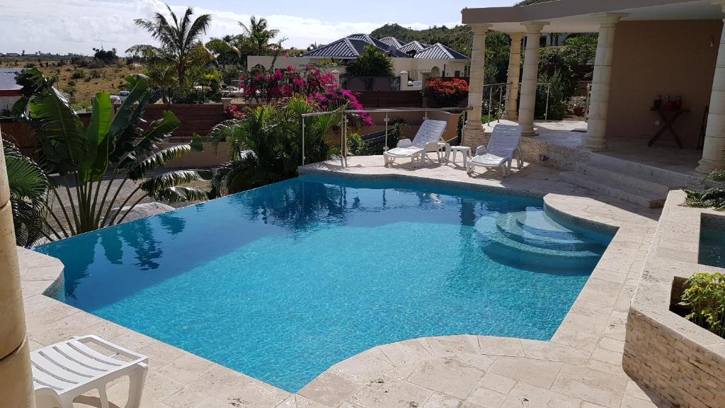 una piscina con 2 sillas y una piscina en C'RENITY VILLA, en Saint Martin