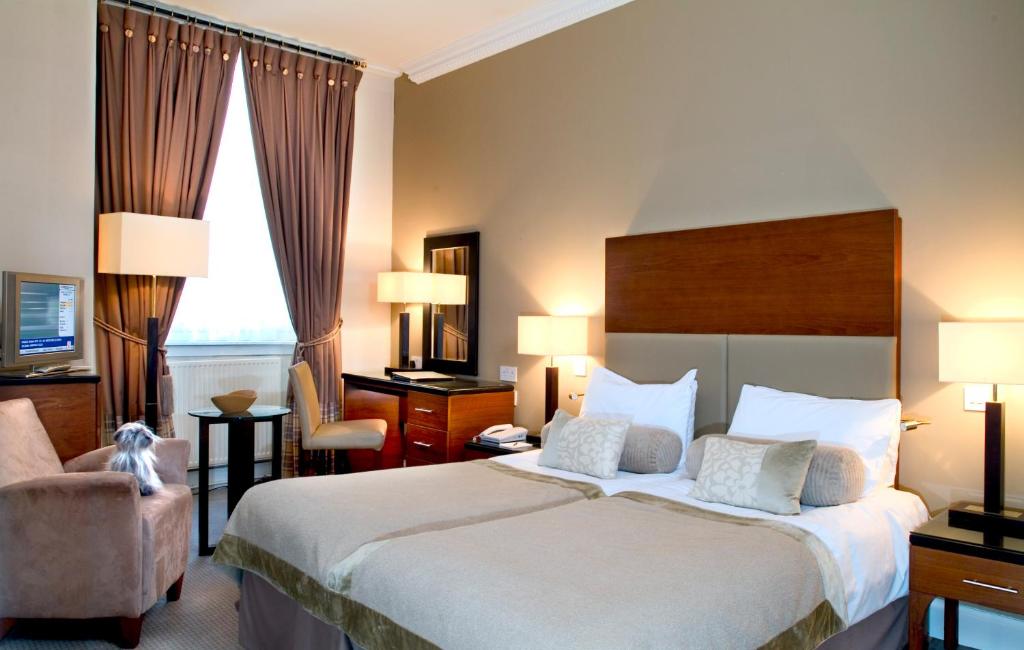 エディンバラにあるザ パーラメント ハウス ホテルの大きなベッドと椅子が備わるホテルルームです。