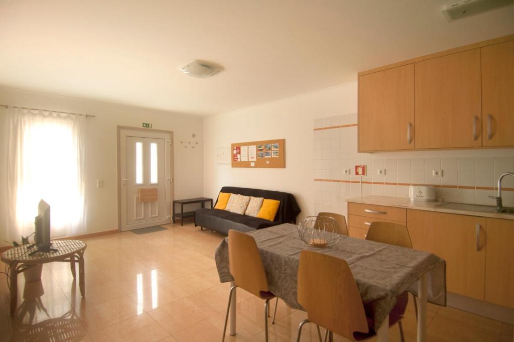 cocina y sala de estar con mesa y sofá en Casa da Tia Matilde, en Sesimbra