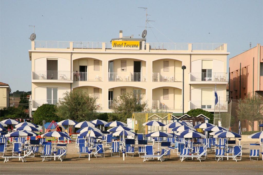 a bunch of chairs and umbrellas in front of a building at Hotel Toscana in Marotta
