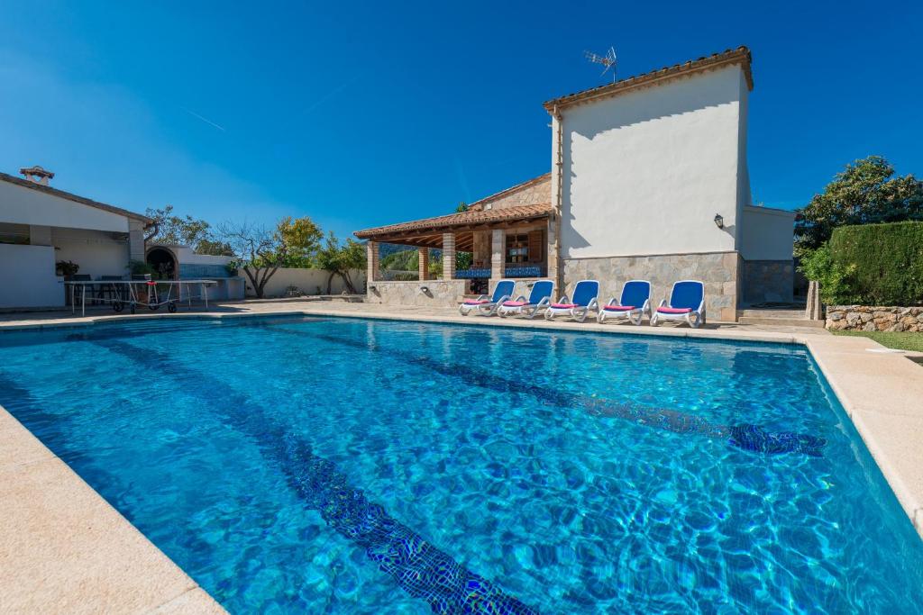 a swimming pool with chairs in front of a house at Villa YESERO in Pollença