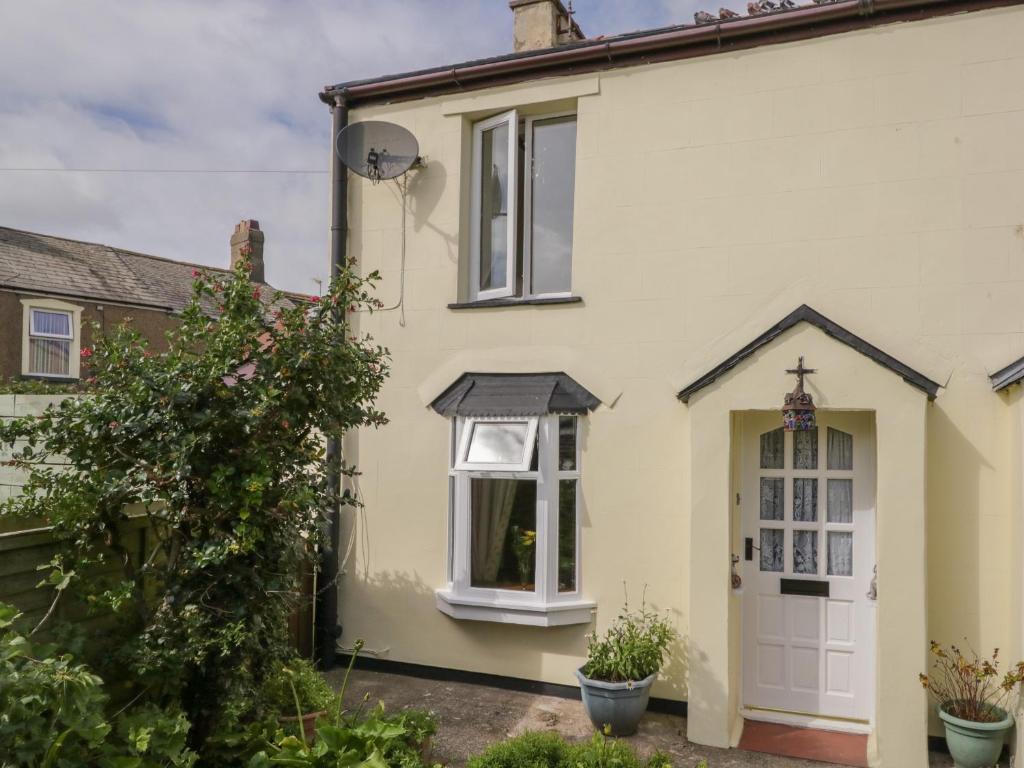a yellow house with a white door and window at Shipwreck Cottage in Millom