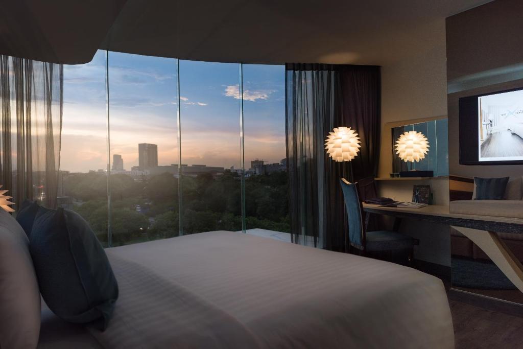 a bedroom with a bed and a desk and a window at The Xtreme Suites in Bangkok