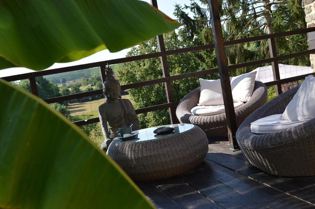 a patio with wicker chairs and a table and a statue at Le Cottage Belmontais, maison individuelle, vue panoramique sur la rivière in Beaumont-sur-Sarthe