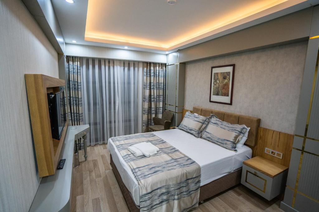 a small bedroom with a bed and a television at Lion City Hotel Kizilay in Ankara