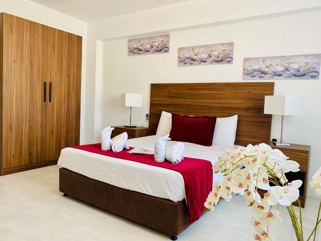 a bedroom with a large bed with a red blanket at Eleonora Hotel Apartments in Larnaka