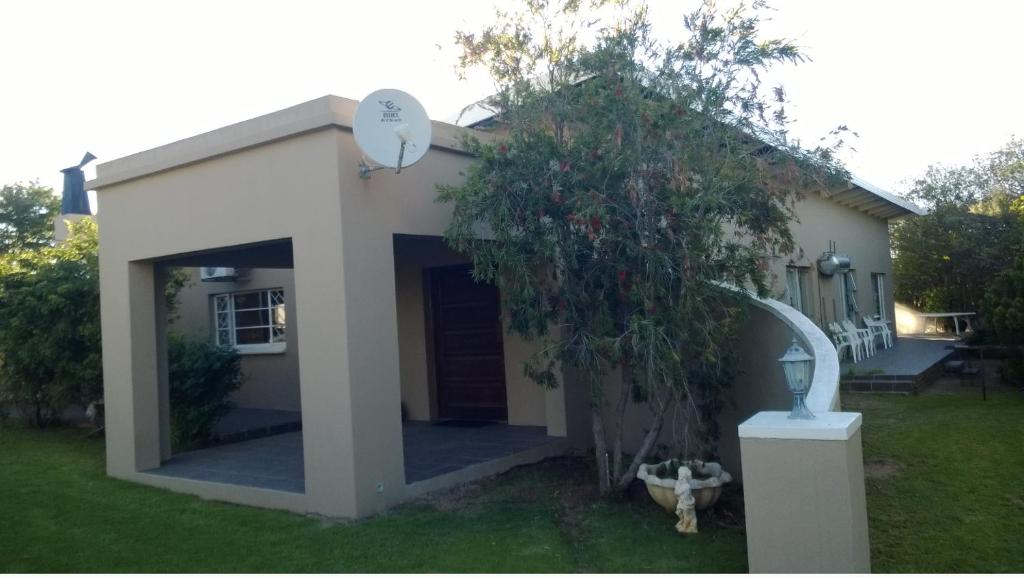 una pequeña casa blanca con un árbol en el patio en Brand Guesthouse, en Colesberg