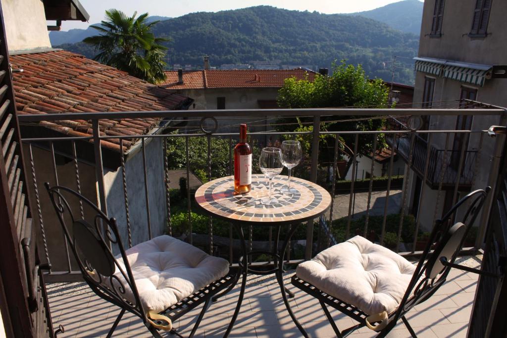 a table and chairs on a balcony with a bottle of wine at Casa all'era in Cernobbio