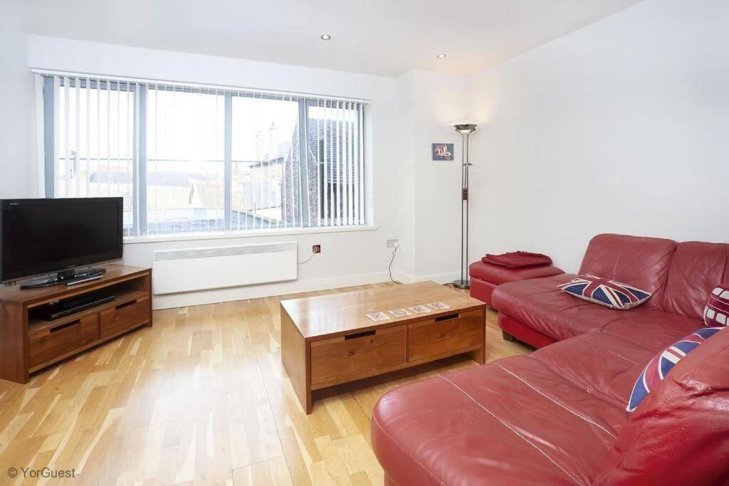 a living room with a red couch and a flat screen tv at Apartment 12 Popeshead Court in York
