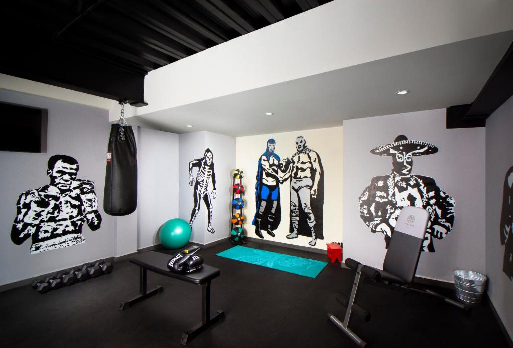A compact hotel gym with boxing equipment, weights and illustrated walls.