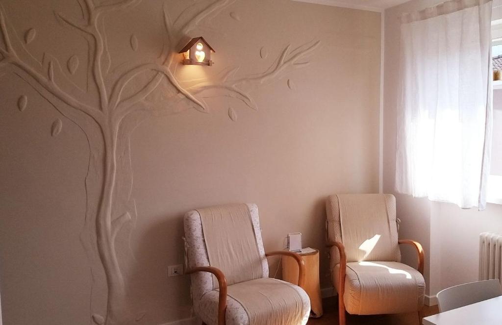 une chambre avec deux chaises et un arbre sur le mur dans l'établissement Appartamento Erica, à Arco
