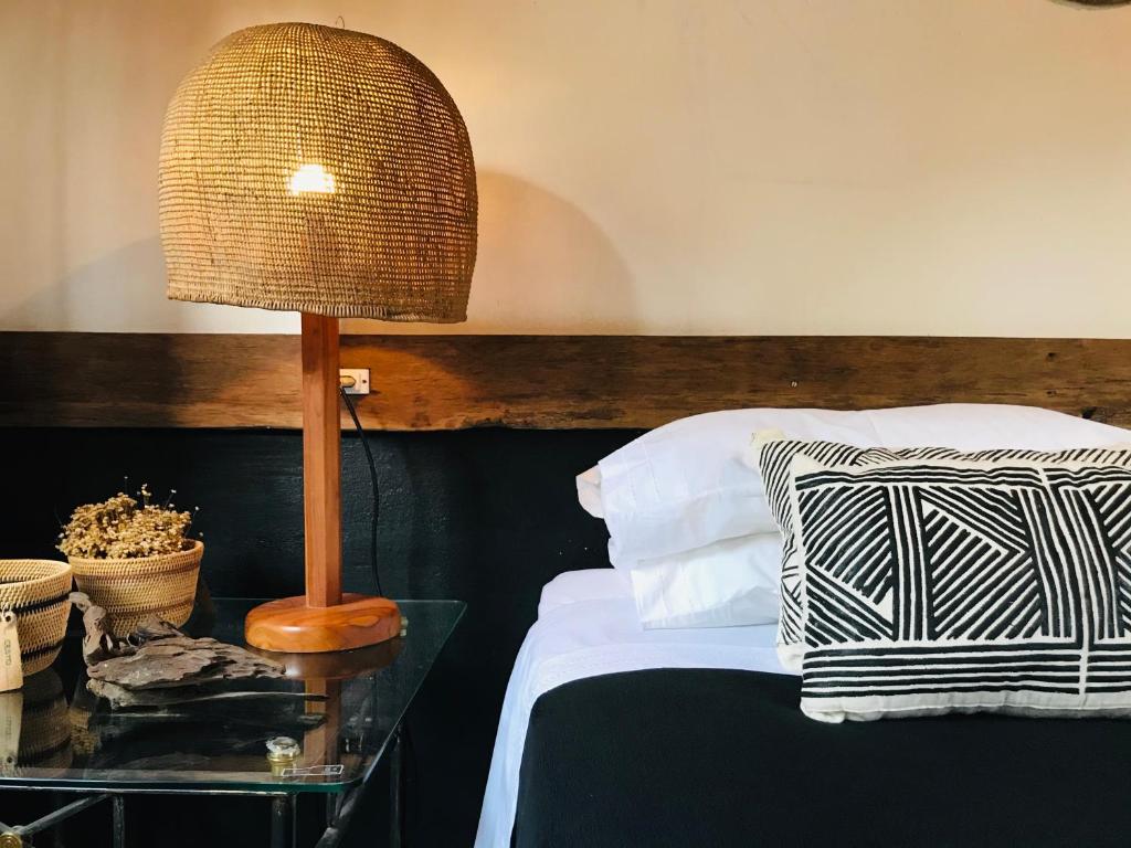 um quarto com uma cama com um candeeiro sobre uma mesa em Quintal da Cuiarana - 50M da praia principal de Alter do Chão em Alter do Chão