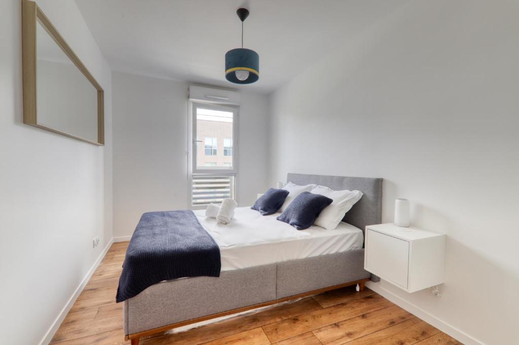 - une chambre blanche avec un lit et des oreillers bleus dans l'établissement Apartment Virtuose - Disneyland Paris 5min - Train station 250m, à Montévrain