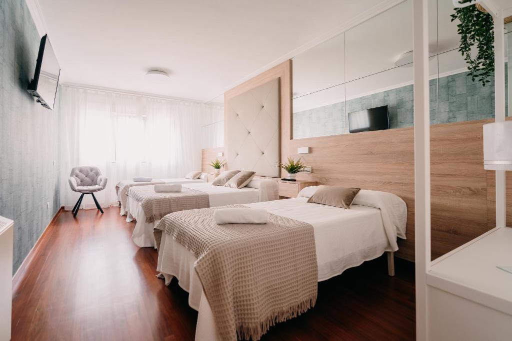a hotel room with two beds and a table at PENSIÓN AUGAS QUENTES in Caldas de Reis