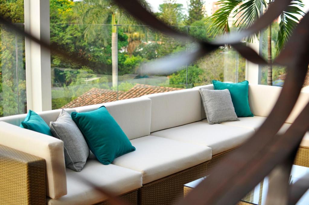 a white couch with blue pillows on a porch at AcquaSanta Lofts Hotel in Cali