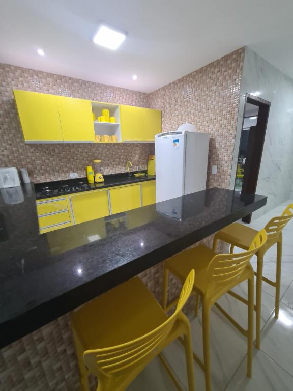 kuchnia z żółtymi szafkami i blatem z żółtymi krzesłami w obiekcie maragogiresidence casa 2 RUA JANGADEIROS 215 w mieście Mar Vermelho