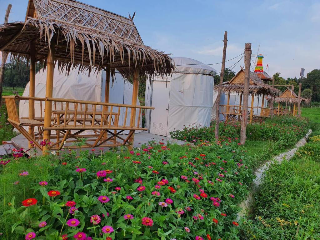 ogród z pawilonem i kwiatami w trawie w obiekcie Baanrimdoi Resort Lampang w mieście Lampang